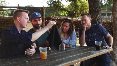 Scott Rowan at a picnic table watching a magic trick on Scam School